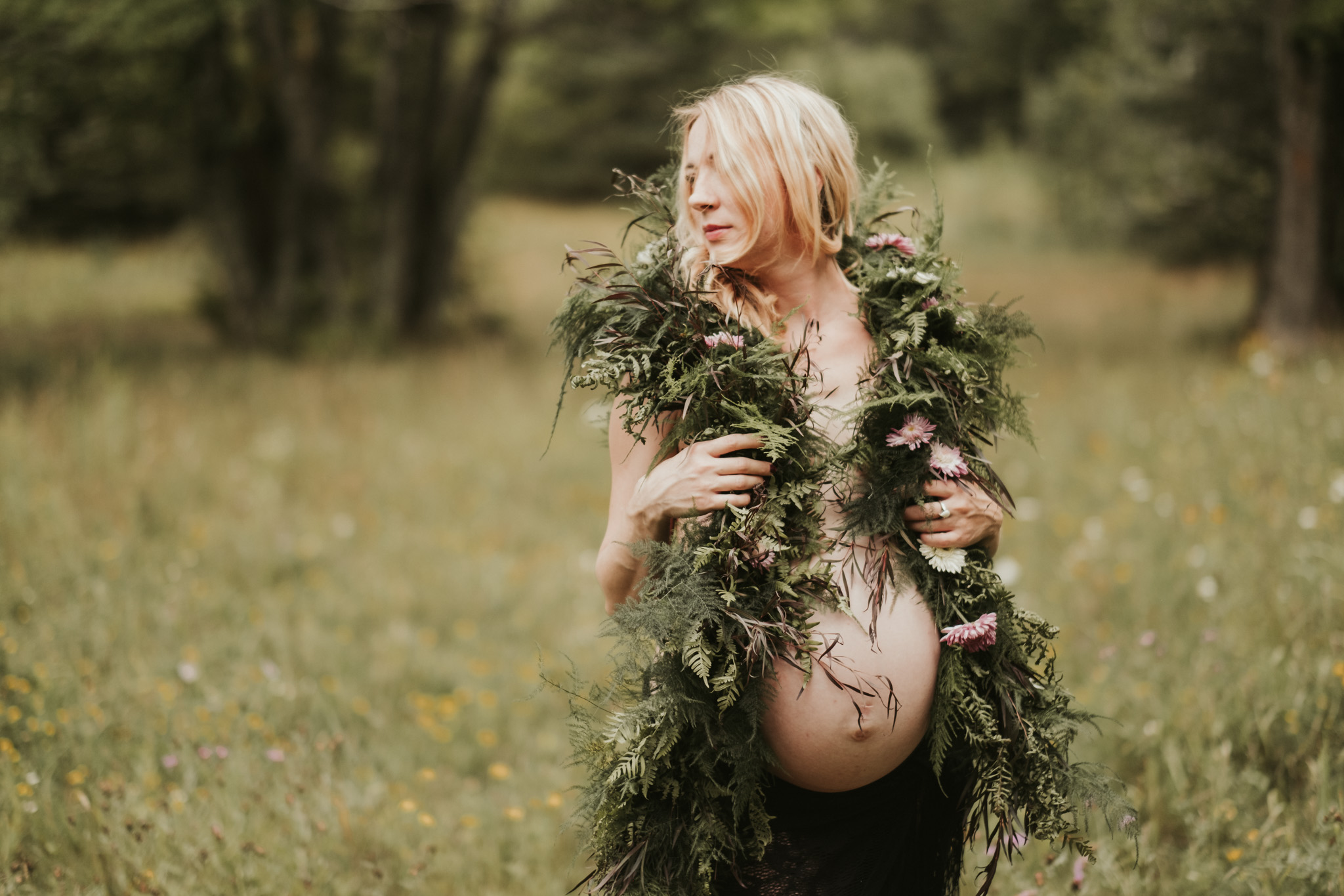 Pregnant woman with floral arrangement near forest
