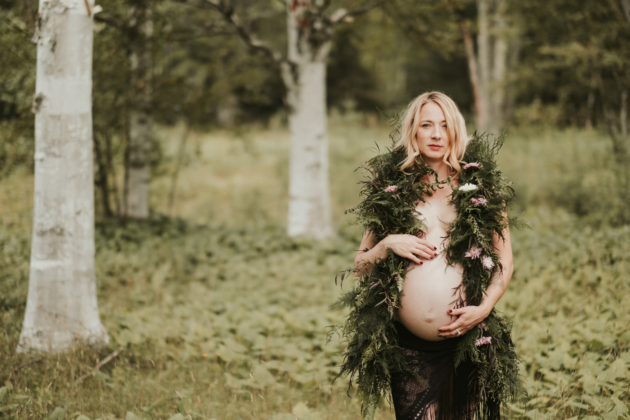 Pregnant woman in forest draped in greenery
